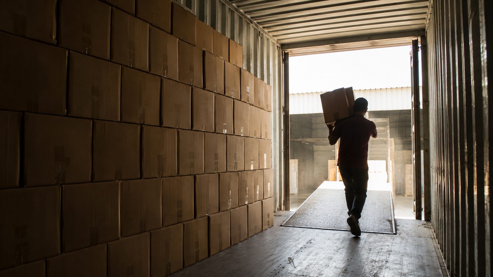 Plain kraft master cartons stacked inside a container during supervised stuffing