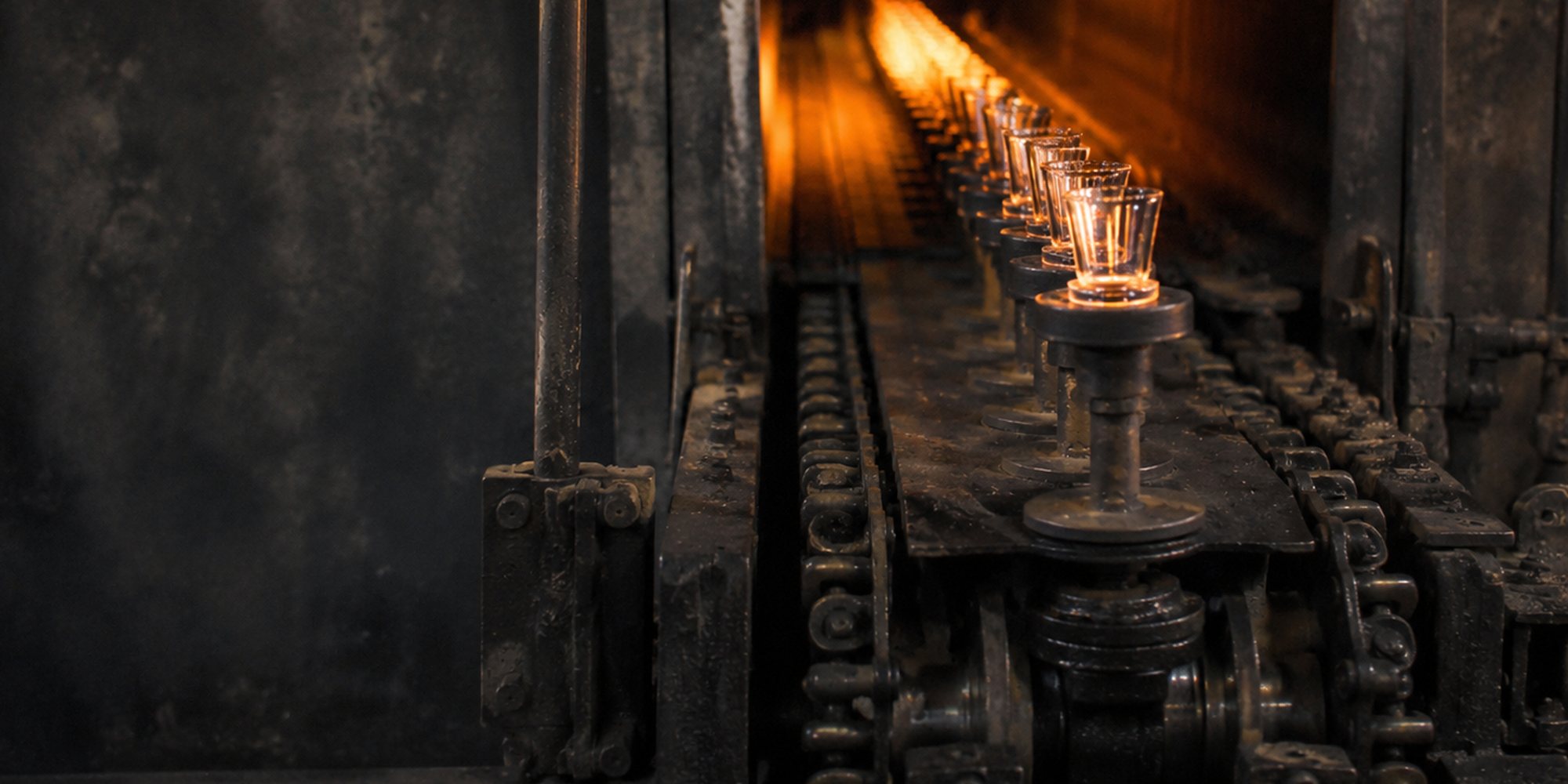 Freshly pressed clear glass tumblers emerging on the conveyor from the glowing annealing lehr at Glastic's factory in Firozabad