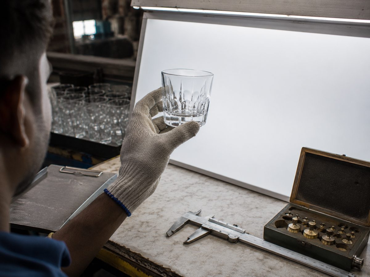A whisky glass on the inspection bench with vernier caliper and weight set for quality control